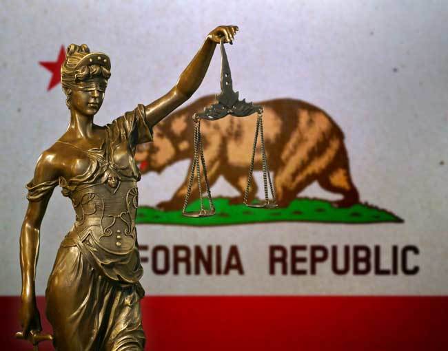 A statue of Justice in front of the California flag