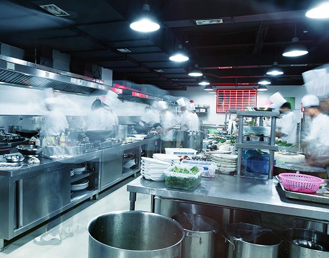 Photo of commercial kitchen with chefs blurred from movement
