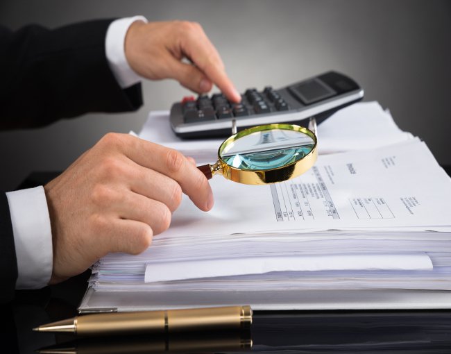 auditor reviewing financial documents with magnifying glass